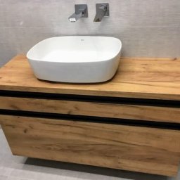 STOLARSTWO PIOTR GŁĄBOWSKI - Nowoczesna łazienka z umywalką nablatową w kształcie kwadratu, osadzoną na szafce z drewnopodobnym fornirem i czarnymi akcentami, minimalistyczne baterie ścienne.