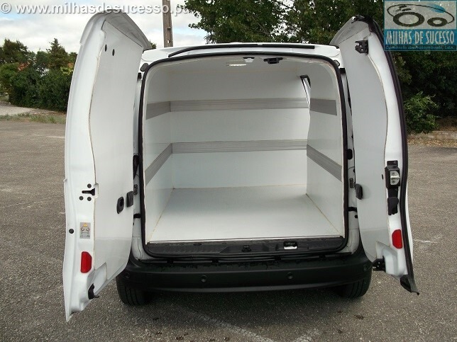 Wnętrze furgonetki dostawczej z otwartymi drzwiami, wyłożone białym tworzywem sztucznym z poziomymi listwami wzmacniającymi.