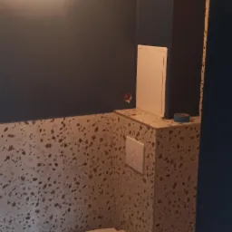 Nowoczesna toaleta podwieszana z mozaikową okładziną ścian i ciemnoniebieską ścianą, widoczna instalacja elektryczna.