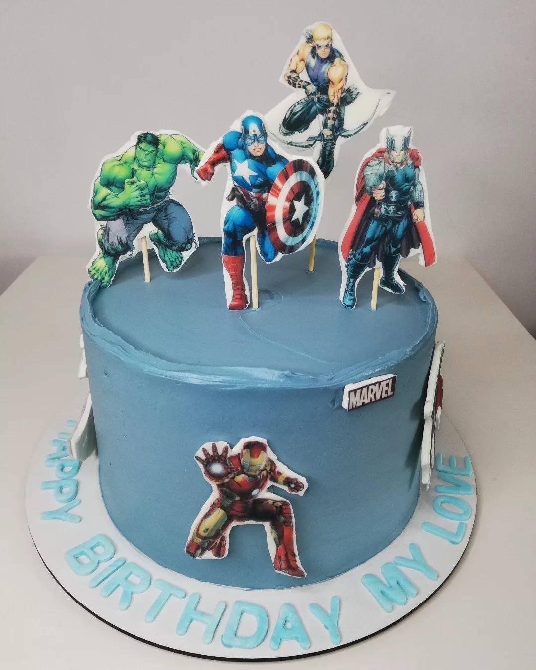 Tort urodzinowy z jasnoniebieskim kremem, dekorowany postaciami z komiksów Marvela: Hulk, Kapitan Ameryka, Thor, Hawkeye i Iron Man, z napisem 'Happy Birthday My Love' na podstawie.