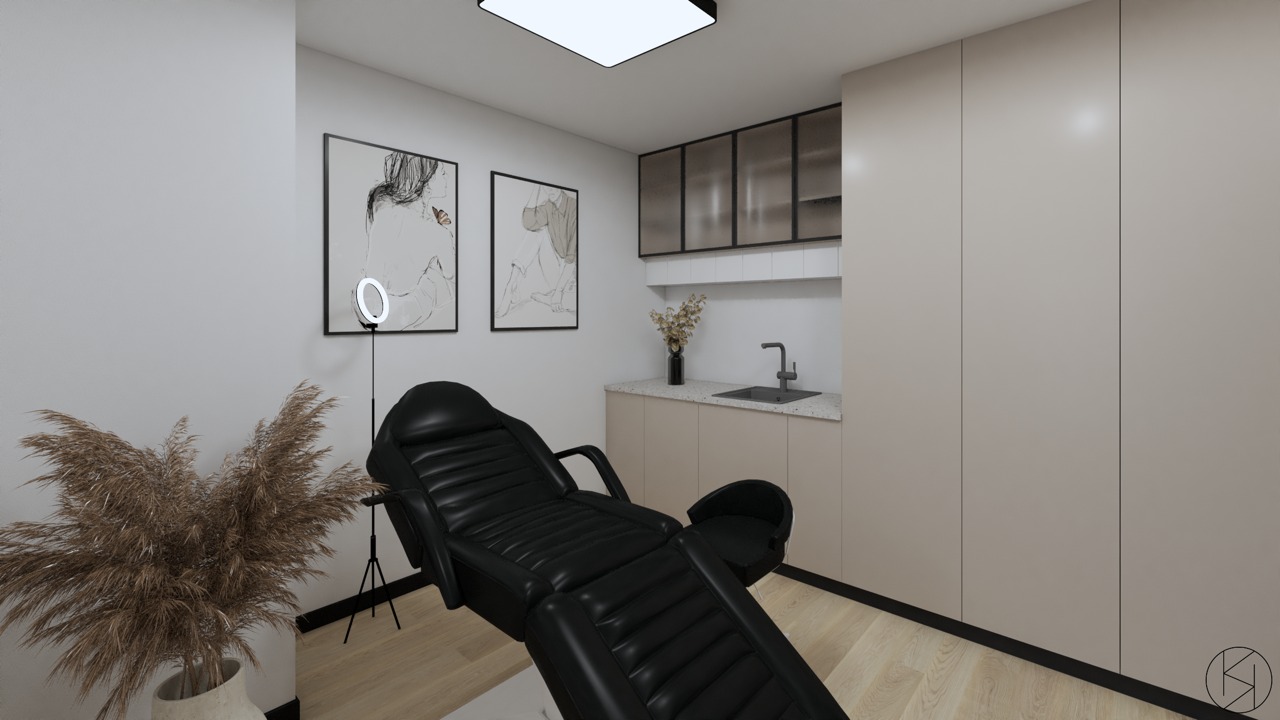Wnętrze gabinetu z czarnym fotelem kosmetycznym, lampą pierścieniową, dekoracjami z suszonych traw, umywalką i minimalistycznymi obrazami na ścianie.