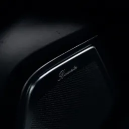 Czarny głośnik samochodowy Burmester z metalową obudową i subtelnym oświetleniem.