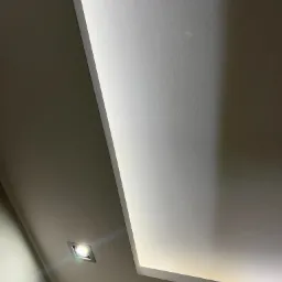 Nowoczesny sufit podwieszany z oświetleniem punktowym i liniowym LED, widok z dołu pod kątem.