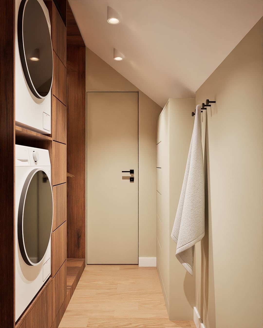 Funkcjonalna pralnia w domu: pralko-suszarka w zabudowie z drewna, beżowe ściany i drzwi, drewniana podłoga, ręcznik na wieszaku. Nowoczesne oświetlenie punktowe.