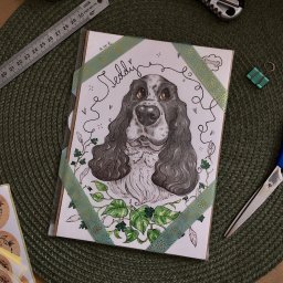 a.er.te - Ręcznie rysowany portret psa rasy Cocker Spaniel o imieniu Teddy, ozdobiony taśmą washi i roślinnymi motywami, leżący na zielonej podkładce.