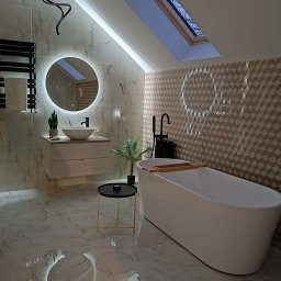 Remonty Volodymyr Muzyka - Nowoczesna łazienka na poddaszu z białą wanną wolnostojącą, umywalką na szafce z okrągłym lustrem LED, marmurową okładziną ścian i podłogi oraz oknem dachowym.