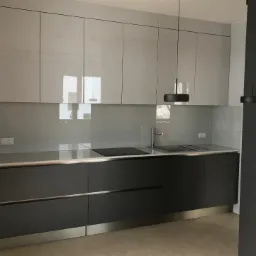 Nowoczesna kuchnia z szarymi, lakierowanymi szafkami górnymi i ciemnoszarymi dolnymi, stalowym blatem, minimalistyczną armaturą i lampami wiszącymi.