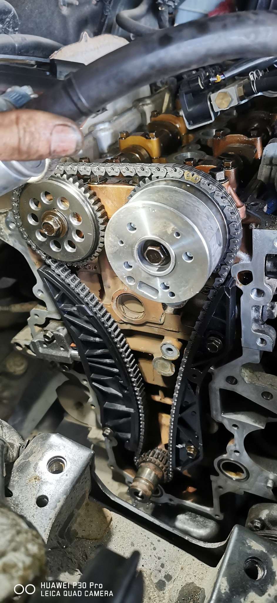 Silnik samochodowy w trakcie naprawy, widoczny rozrząd z łańcuchem, koła zębate i napinacz łańcucha, zbliżenie na mechanizm.