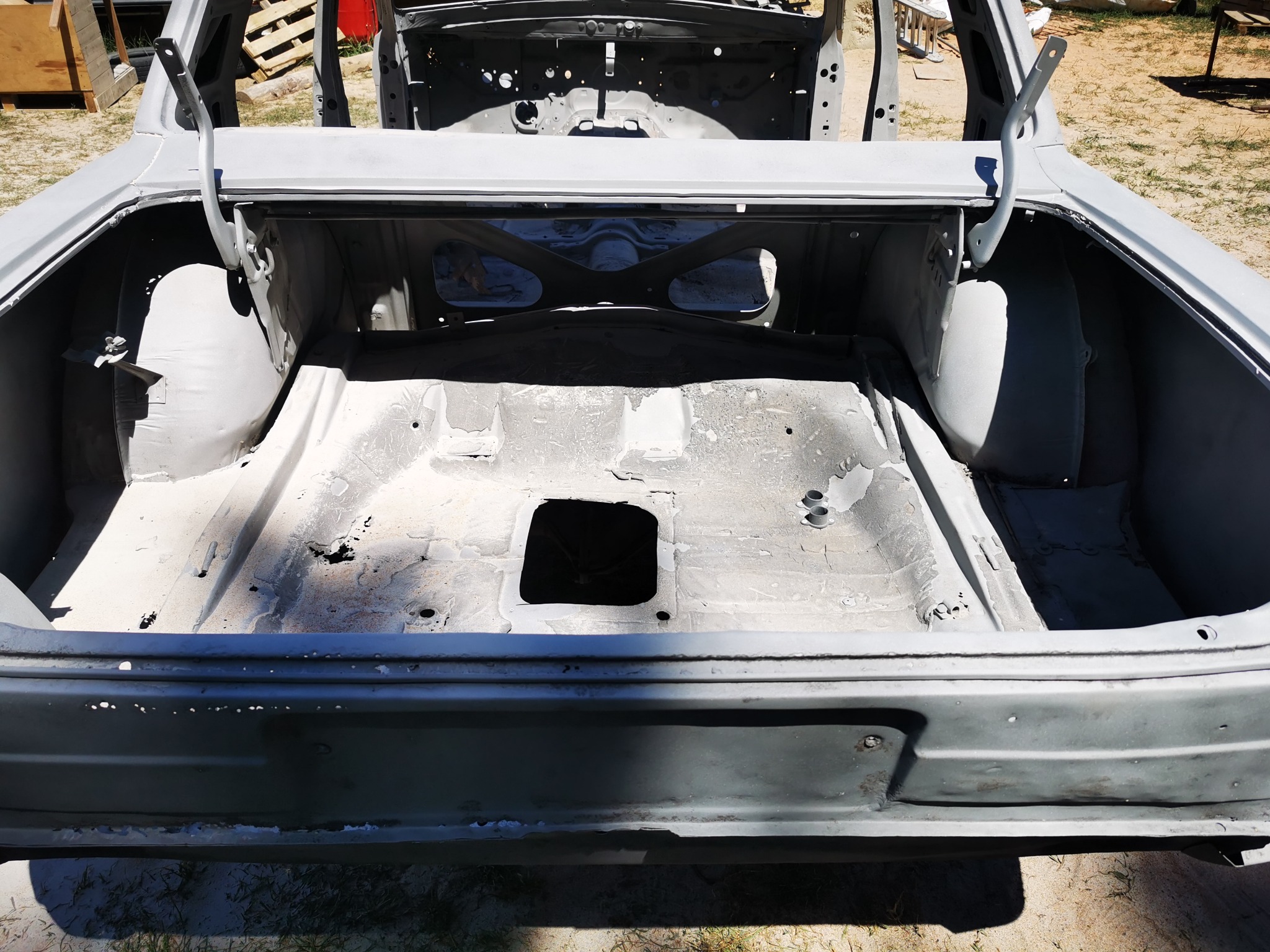 Wnętrze bagażnika samochodu po oczyszczeniu z rdzy, przygotowane do dalszych prac blacharskich i lakierniczych, widoczne ślady korozji.