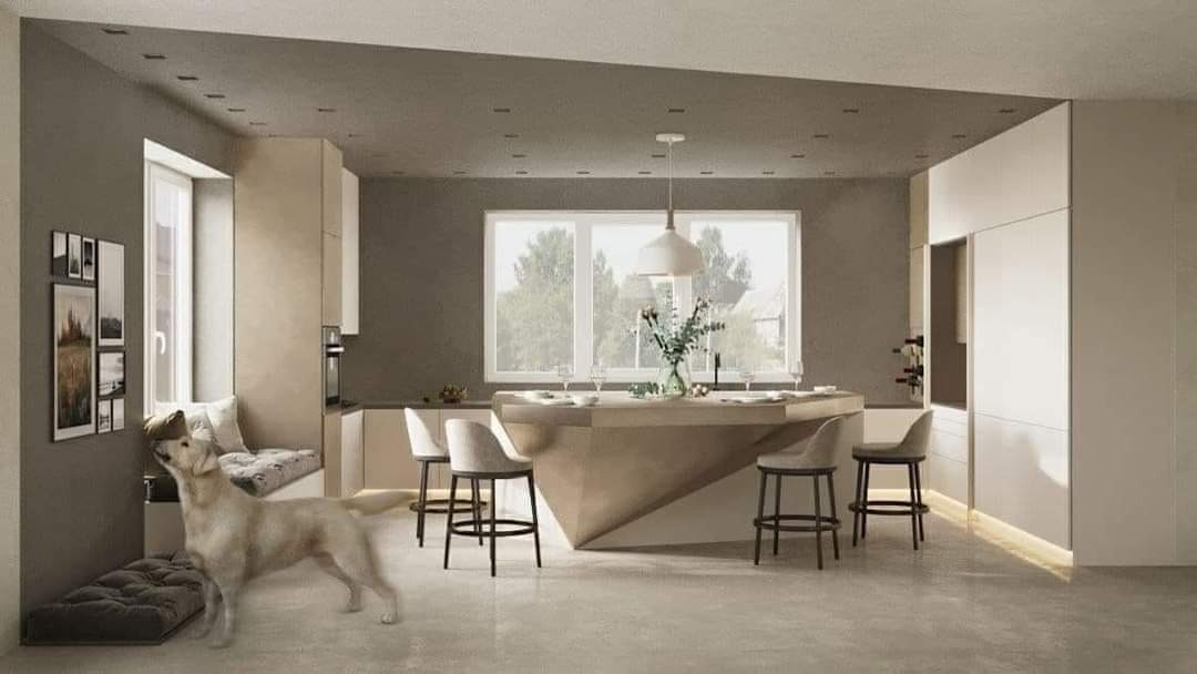 Nowoczesna kuchnia z wyspą, jasnymi meblami i dużym oknem; pies rasy labrador stoi przy ścianie z galerią obrazków.