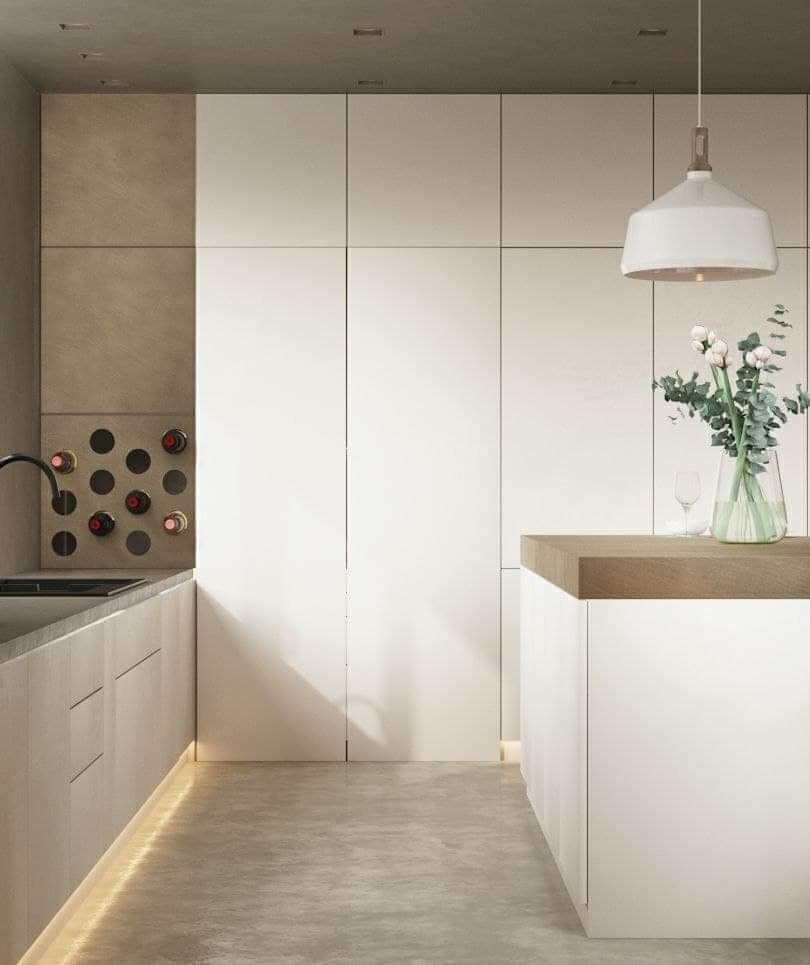Minimalistyczna kuchnia z białymi szafkami bez uchwytów, wyspą z drewnianym blatem, wbudowanym regałem na wino i oświetleniem LED pod szafkami.