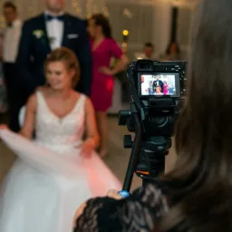 Podgląd nagrania ślubnego na ekranie kamery Sony z zamontowanym mikrofonem, z widoczną panną młodą w białej sukni w tle.