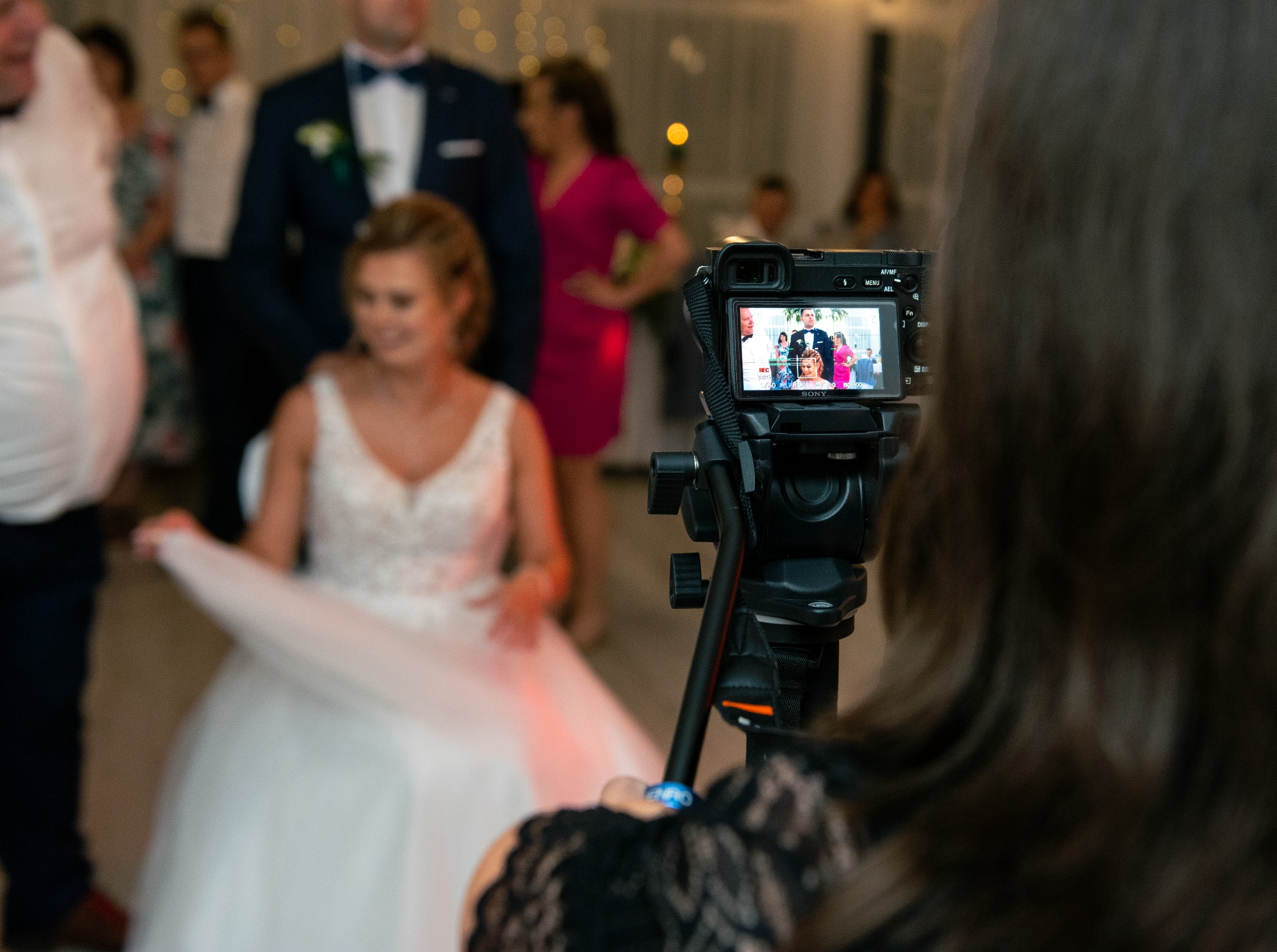 Podgląd nagrania ślubnego na ekranie kamery Sony z zamontowanym mikrofonem, z widoczną panną młodą w białej sukni w tle.