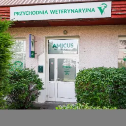 Fasada budynku z zielonym napisem 'Przychodnia Weterynaryjna' i logo, wejście do placówki 'Amicus'.