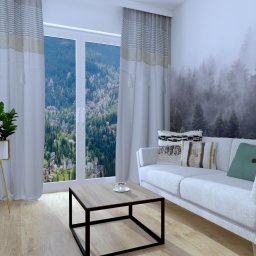 KS PROJECT Sp. z o.o. - Wizualizacja salonu z szarą sofą, stolikiem kawowym z filiżanką, telewizorem, komodą i rośliną w złotej doniczce na tle okna z widokiem na góry i fototapety z motywem lasu we mgle.