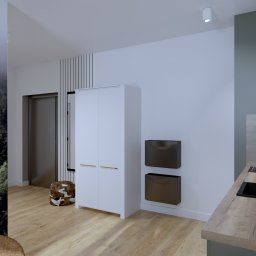 KS PROJECT Sp. z o.o. - Wizualizacja małego mieszkania inwestycyjnego: minimalistyczna kuchnia z drewnianym blatem, czarnym zlewem i baterią, biała szafa na tle ściany z motywem lasu, dekoracyjny puf w zwierzęcy wzór.