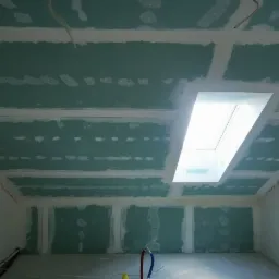 Montaż sufitu podwieszanego z płyt gipsowo-kartonowych ze świetlikiem w Pszczynie, widoczne łączenia i szpachlowanie.