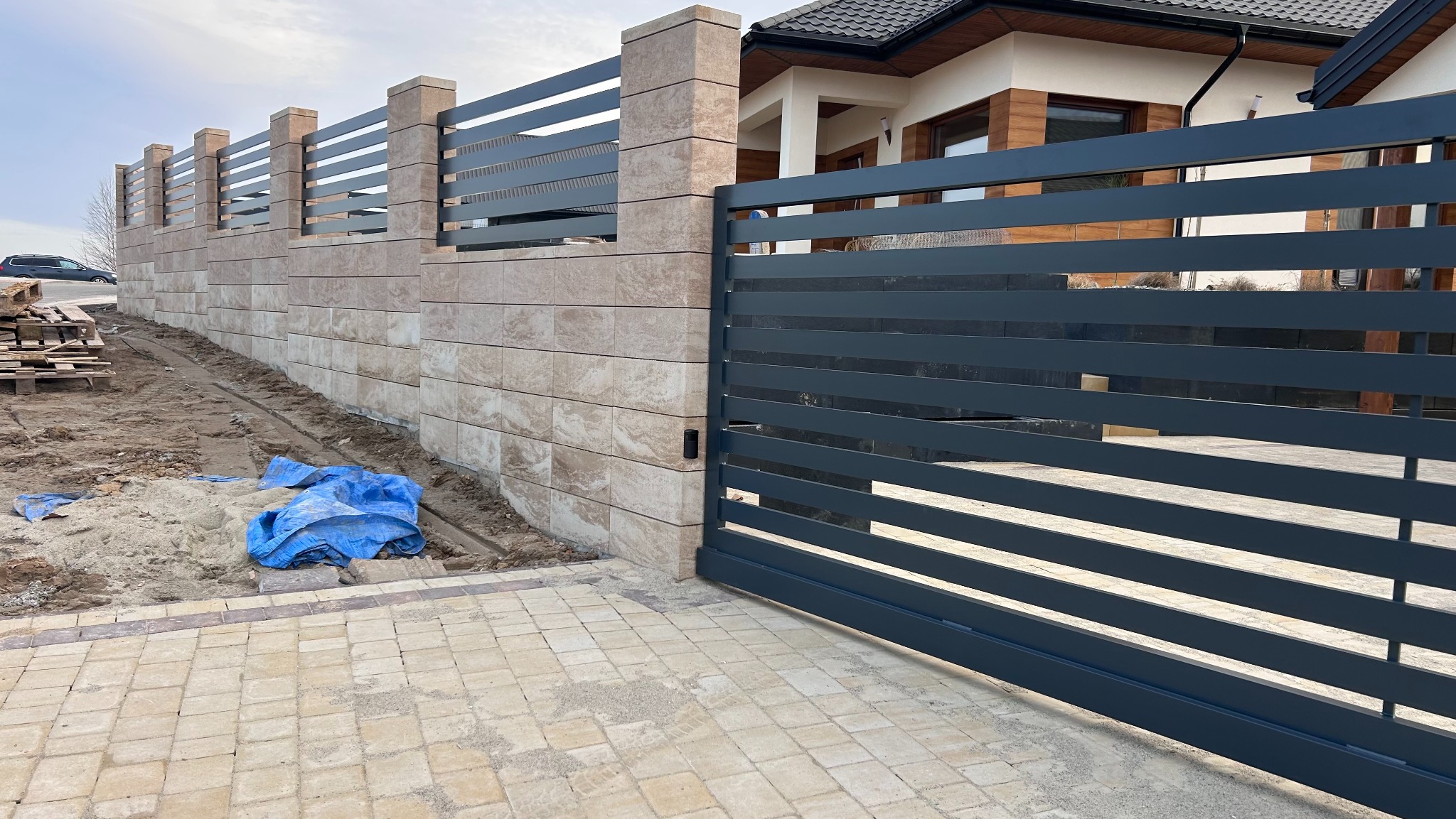 Nowoczesne ogrodzenie z metalową bramą przesuwną i kamiennymi słupkami w Gnojnicy. Połączenie elegancji i trwałości, widok z zewnątrz posesji.