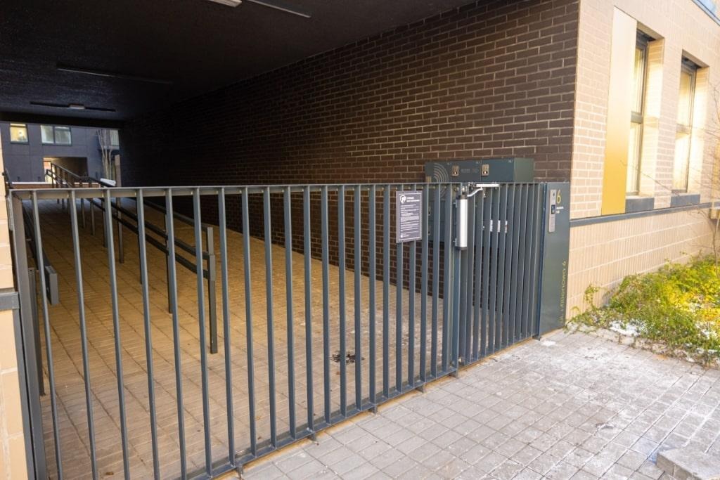 Metalowa barierka z pionowych prętów, zabezpieczająca wjazd do wnęki budynku w Częstochowie, z widoczną rampą dla wózków inwalidzkich w tle.