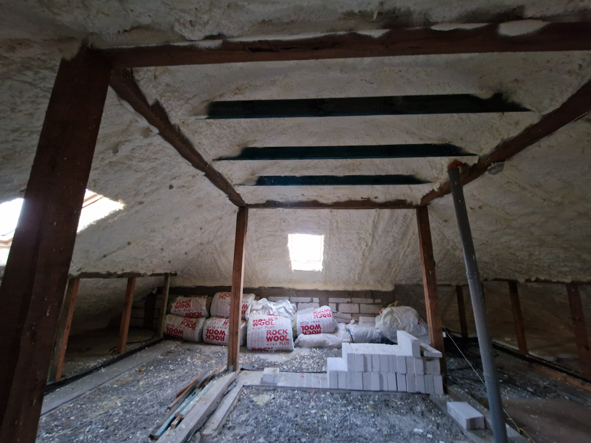 Poddasze ocieplone pianką PUR z widocznymi workami wełny mineralnej Rockwool i bloczkami Ytong, przygotowane do dalszych prac wykończeniowych.