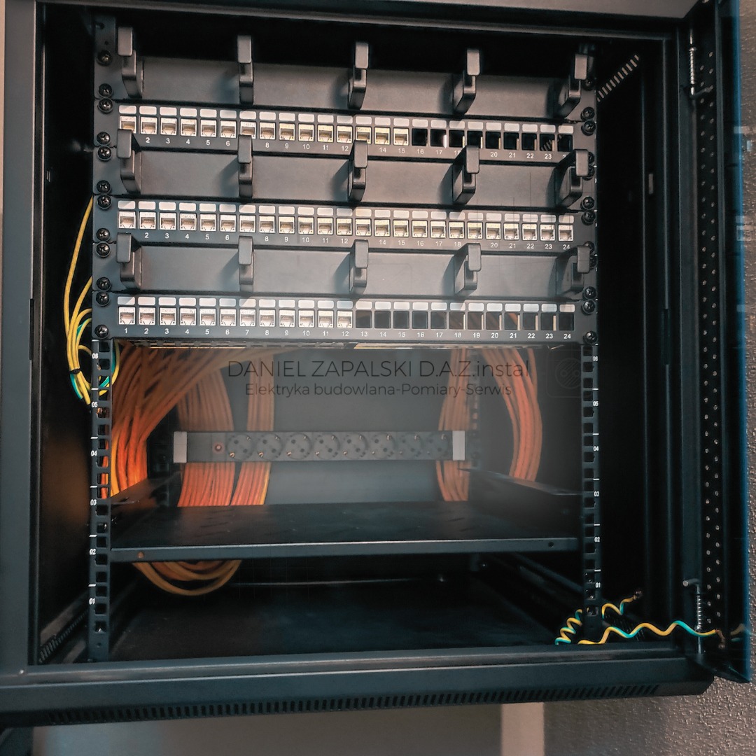 Panel krosowniczy z ponumerowanymi portami, okablowanie w szafie rack, widoczne przewody pomarańczowe i żółto-zielone.