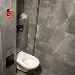 Michał Majcher - Szara łazienka z marmurowymi płytkami, częściowo wykończona, z widoczną instalacją elektryczną i stelażem podtynkowym do WC.