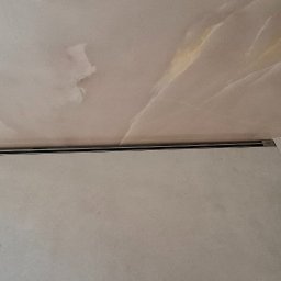 Wiktor Kharchenko usługi budowlane - Wykończona łazienka z marmurową teksturą na suficie i ścianach, z widoczną listwą oświetleniową LED zamontowaną w rogu.