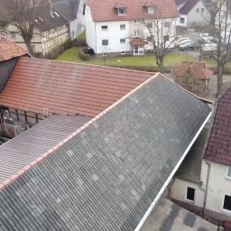 BART-DACH - Widok z góry na dachy budynków w niemieckiej miejscowości, z widoczną częściowo zdemontowaną konstrukcją dachu jednego z budynków i materiałami budowlanymi obok.