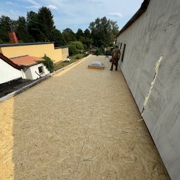 BART-DACH - Płyty OSB ułożone na dachu z widocznym świetlikiem dachowym i pracownikiem w tle, widok z góry na przygotowany dach przed dalszymi pracami dekarskimi.