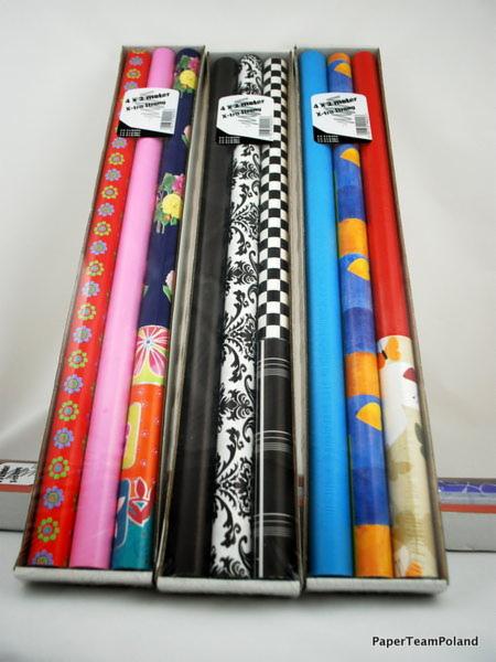 Zestaw czterech rolek papieru ozdobnego w pudełkach, z różnymi wzorami: kwiaty, ornamenty, szachownica i abstrakcyjne kształty.