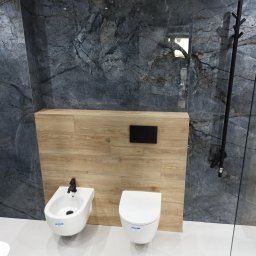 Barański Remonty i Wykończenia - Nowoczesna łazienka z marmurowymi płytkami i drewnopodobną zabudową. Białe bidet i toaleta podwieszana z czarną armaturą. Minimalistyczny design.
