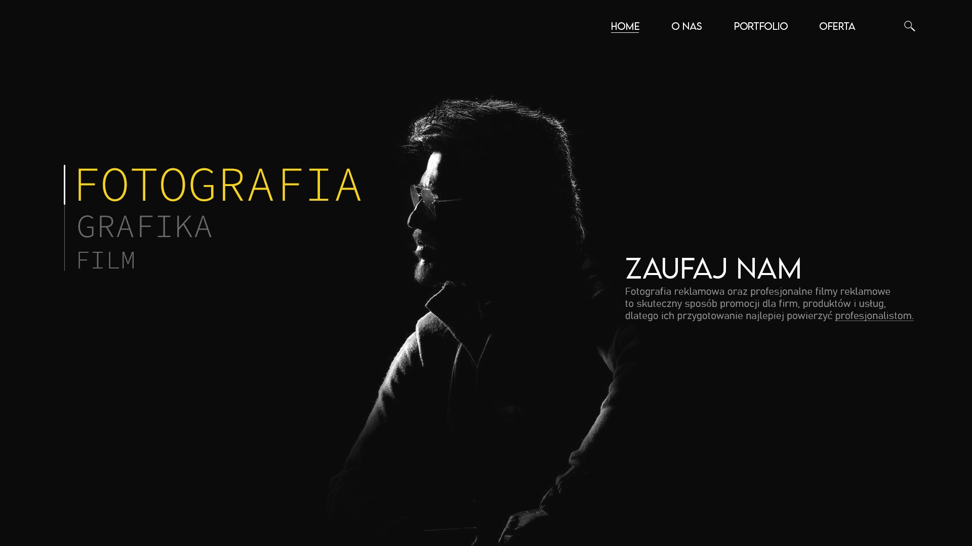 Strona internetowa z minimalistycznym designem, prezentująca ofertę usług fotograficznych, graficznych i filmowych. Zarys sylwetki mężczyzny w okularach w kontraście z czarnym tłem.
