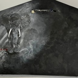 Marta Karpisz - tynkowanie dekoracyjne - Ściana w pokoju z szarą, rozmytą teksturą, na której namalowany jest motyw afrykański: słoń i drzewa sawanny. Widoczne wystające kable i puszki elektryczne.