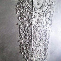 Marta Karpisz - tynkowanie dekoracyjne - Dekoracyjna ściana z tynkiem strukturalnym przedstawiająca wizerunek Meduzy otoczonej roślinnymi ornamentami, wykonana w odcieniach szarości.