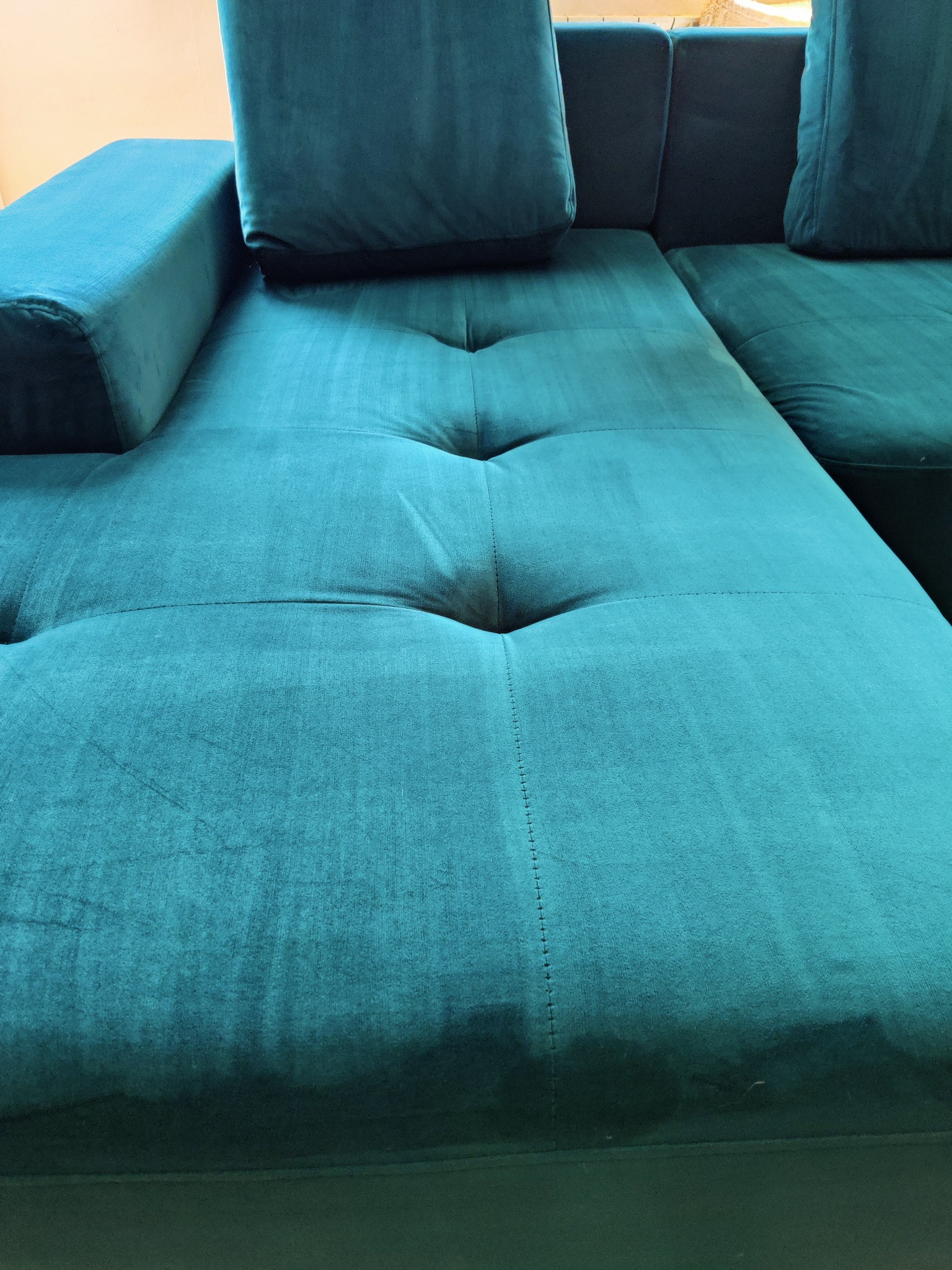 Turkusowa kanapa modułowa z widocznymi plamami po czyszczeniu na siedzisku i oparciu, kontrastujące z czystą powierzchnią, wskazujące na etapowe pranie tapicerki.