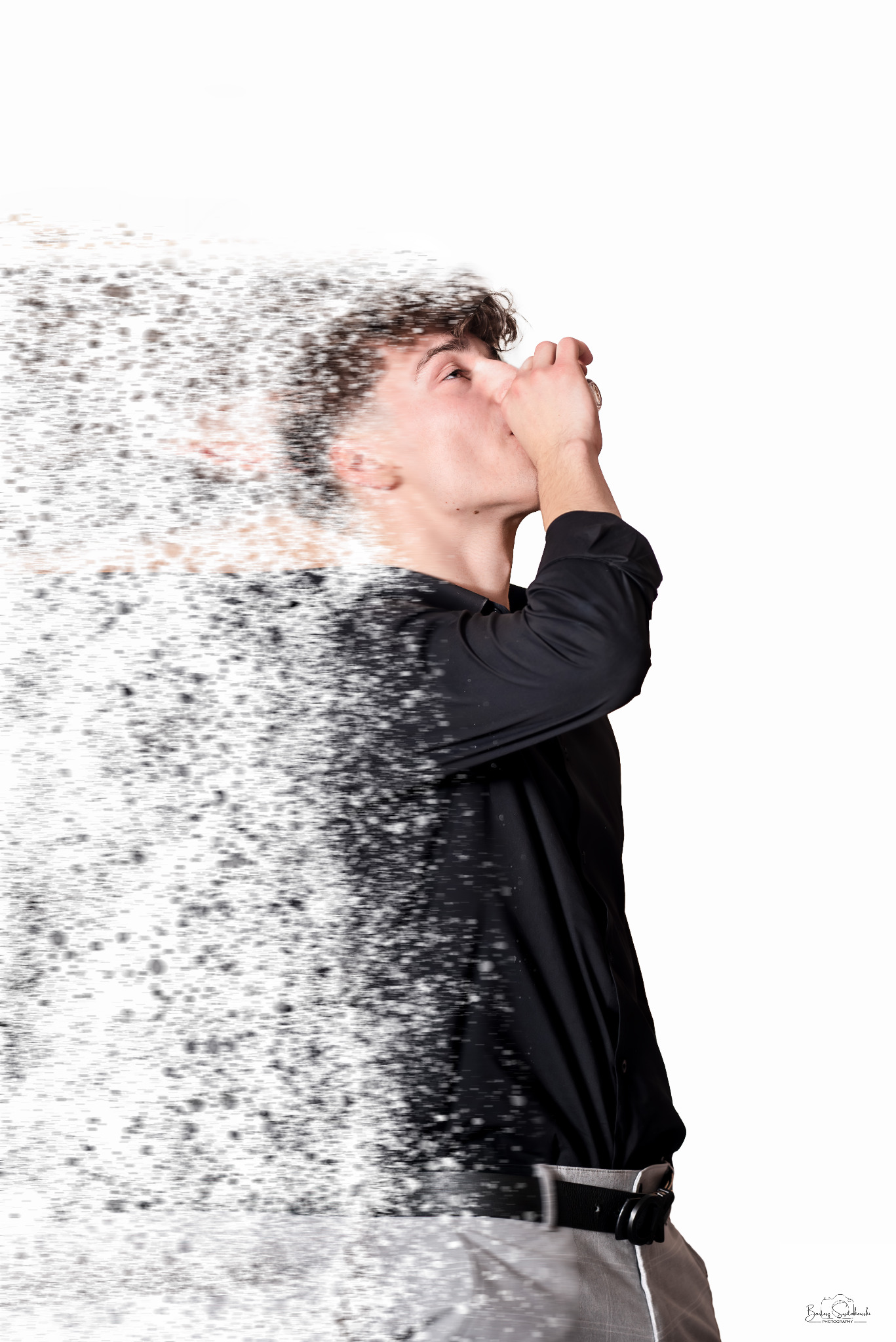 Młody mężczyzna w czarnej koszuli, z efektem rozprysku pikseli, patrzy w górę