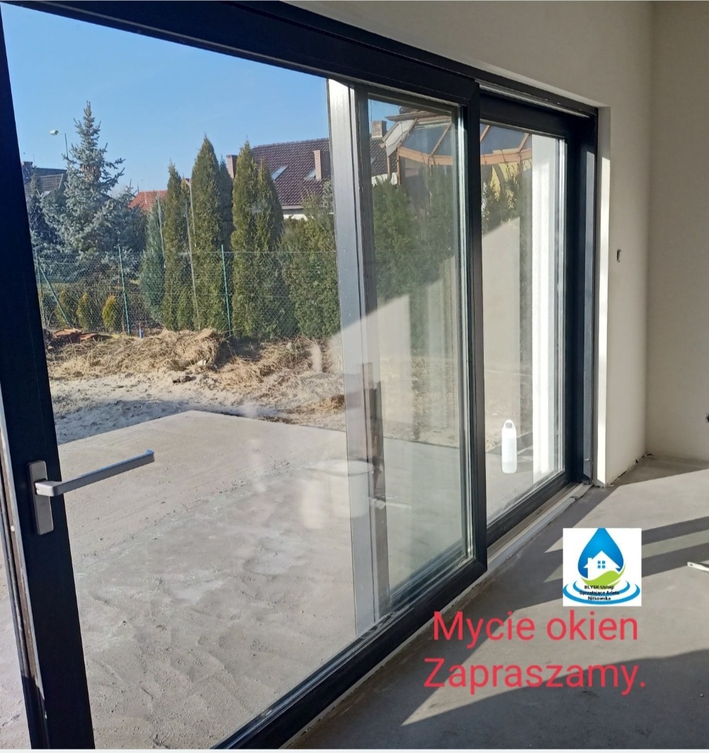 Czyste, przesuwne okno tarasowe w Inowrocławiu, z widokiem na ogród. Widoczne odbicie nieba i drzew w szybie. Nowoczesny design, czarne ramy okienne.
