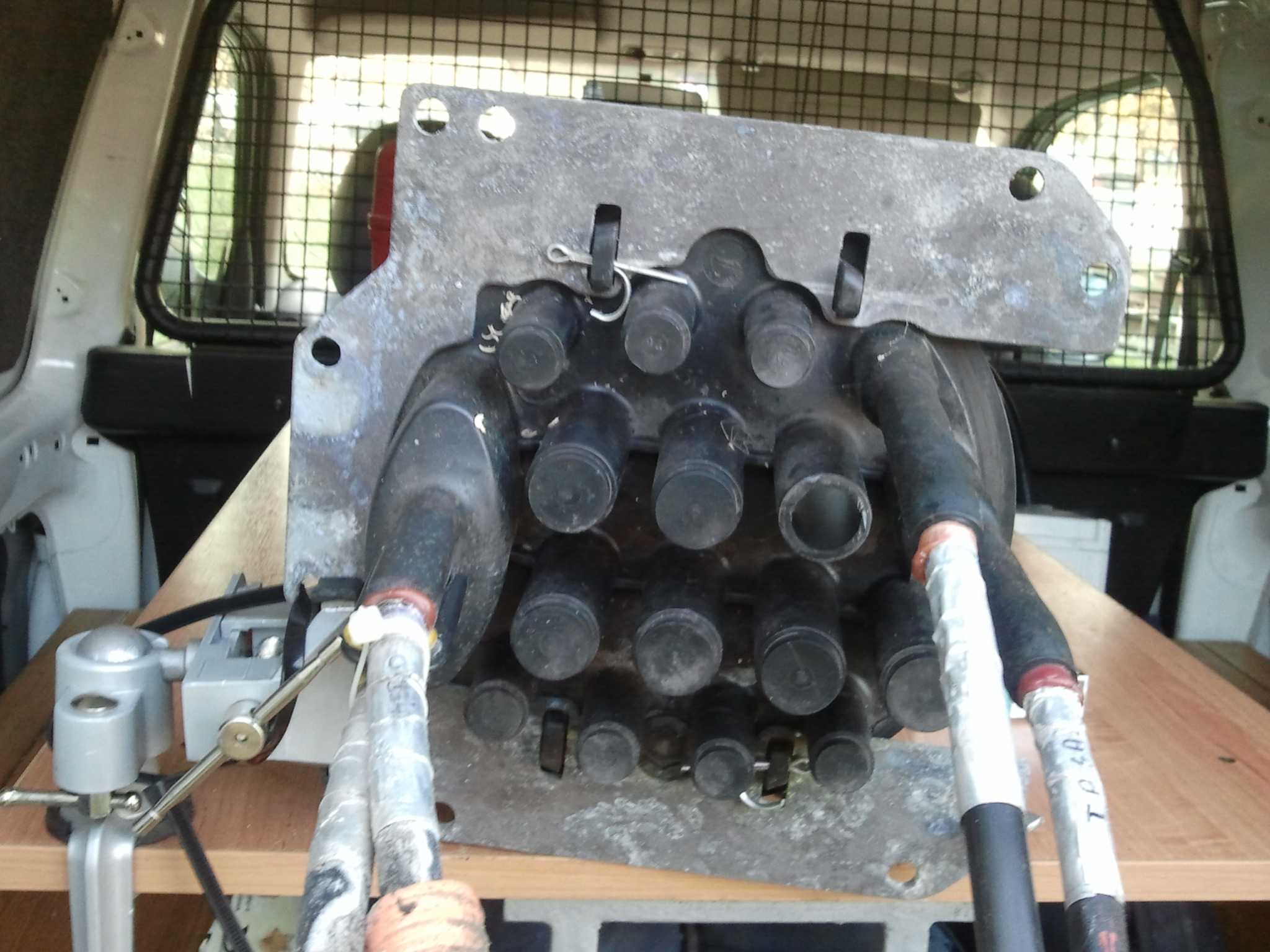 Wiązka kabli telekomunikacyjnych w trakcie montażu wewnątrz pojazdu, zabezpieczona taśmą izolacyjną z napisem, zamocowana w uchwycie narzędziowym.