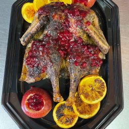 Planbar - Pieczona kaczka polana sosem żurawinowym, dekorowana grillowanymi pomarańczami i jabłkami z żurawiną, ułożona na czarnej tacy.