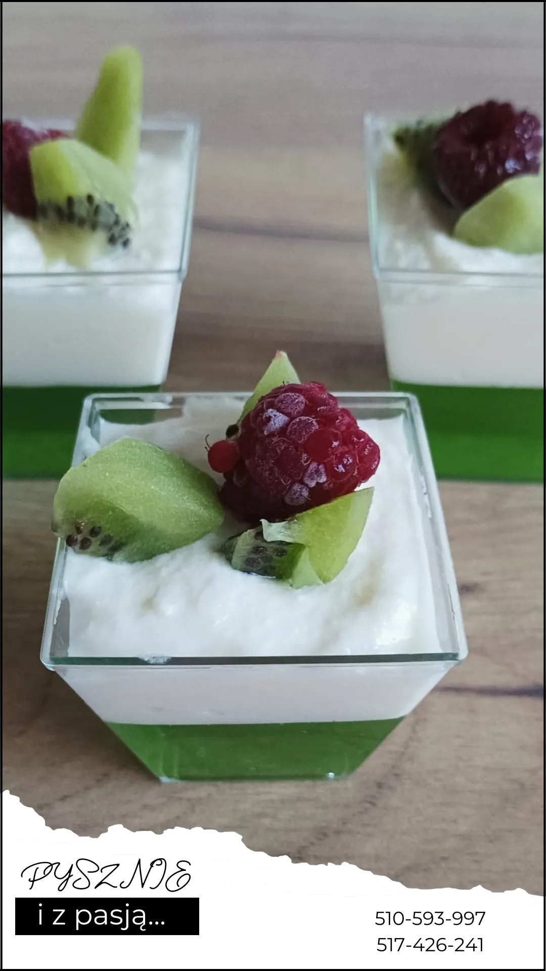 Deser w przezroczystym kubeczku z zieloną galaretką, kremem i owocami: maliną i kiwi, na drewnianym blacie. Widoczne trzy porcje deseru.