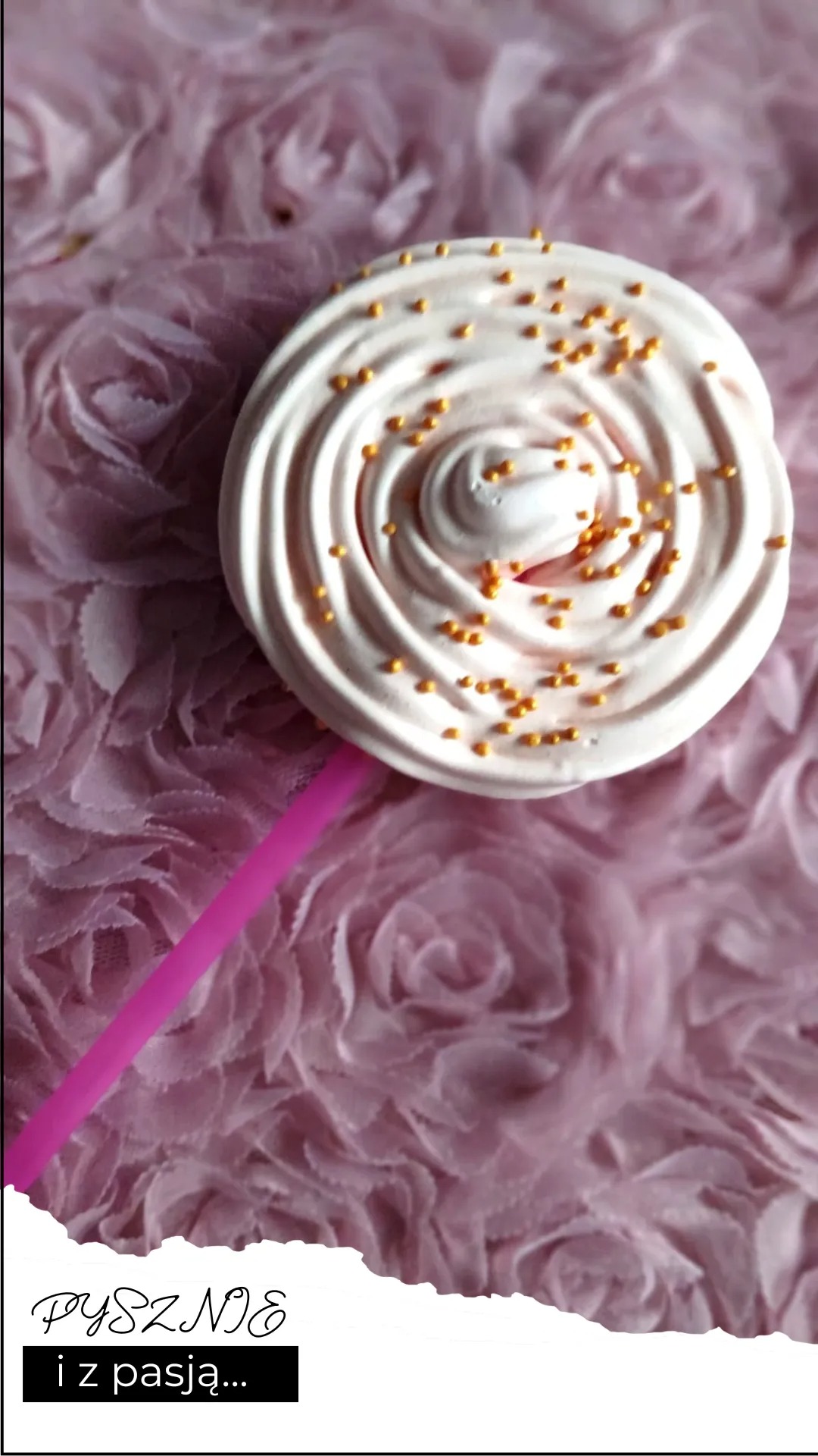 Meringue lollipop decorated with golden sprinkles, presented on a textured pink floral background.