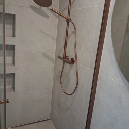 EMES Wykończenia wnętrz - Wykończona łazienka z szarymi płytkami i miedzianą armaturą: deszczownica, bateria termostatyczna i kabina prysznicowa z miedzianymi profilami. W ścianie wnęki.