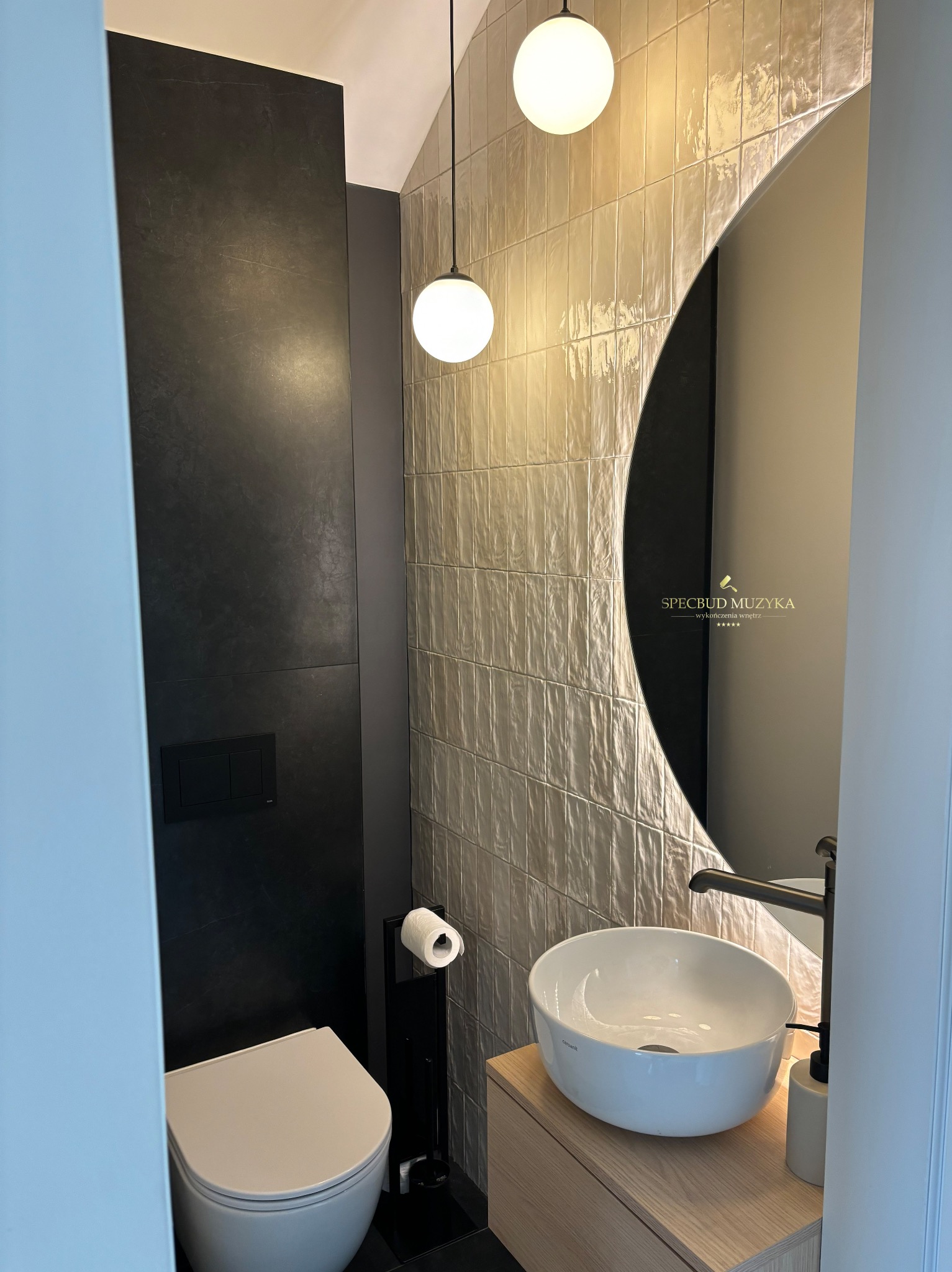 Nowoczesna łazienka z czarnymi płytami, beżowymi płytkami 3D, okrągłym lustrem z podświetleniem i umywalką nablatową