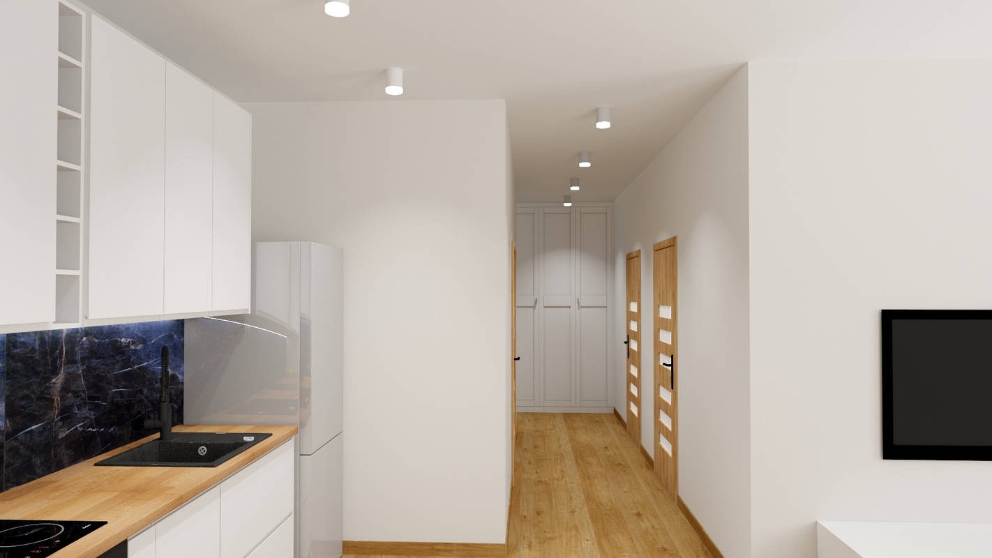 Wnętrze mieszkania z aneksem kuchennym: białe szafki z drewnianym blatem, czarny zlewozmywak na tle ściany z ciemnego marmuru, w tle korytarz z drewnianą podłogą, biała szafa wnękowa i dwoje...