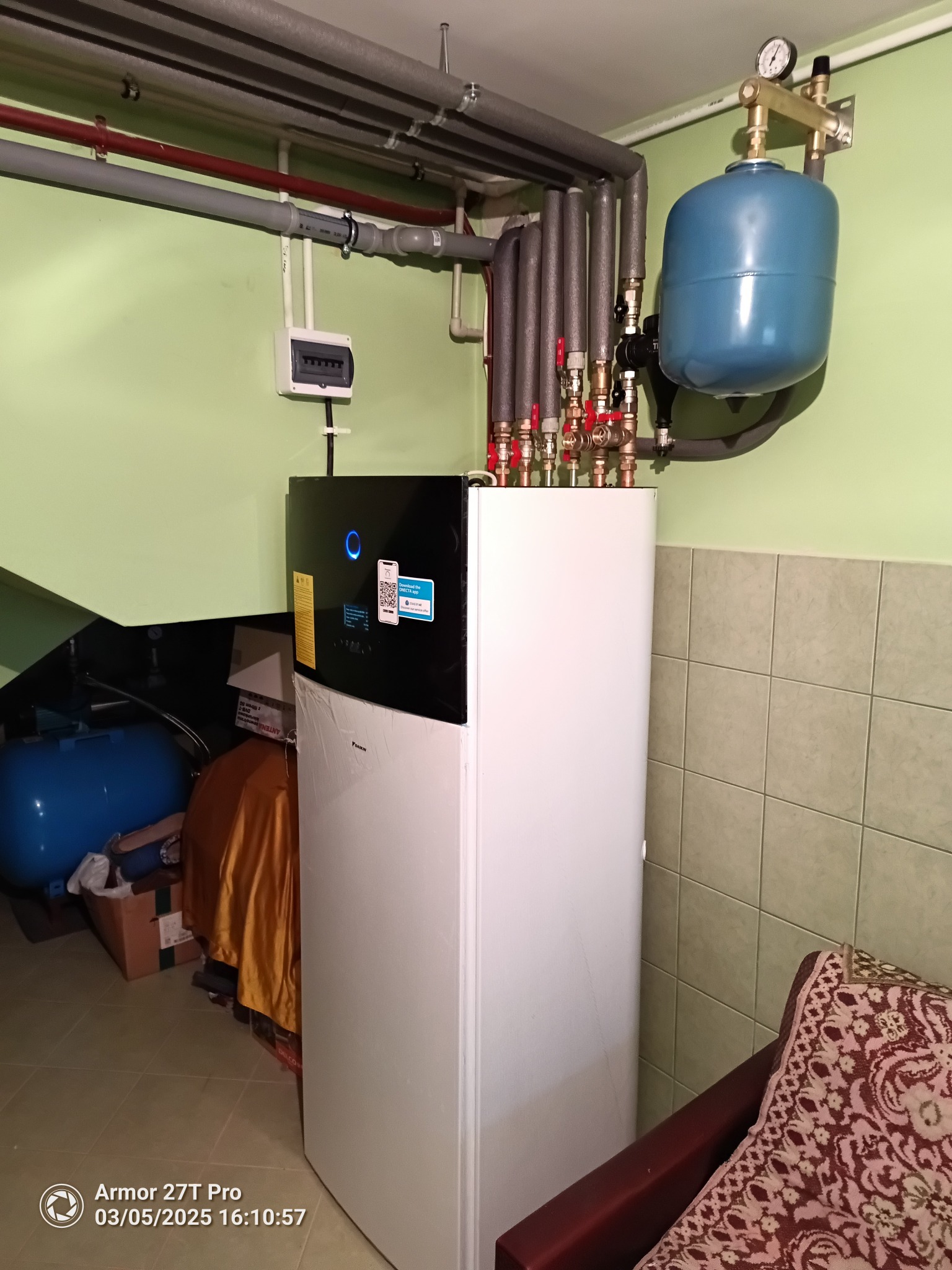 Nowoczesna pompa ciepła Daikin w kotłowni z widoczną instalacją hydrauliczną i zbiornikiem wyrównawczym. Rury w izolacji termicznej.