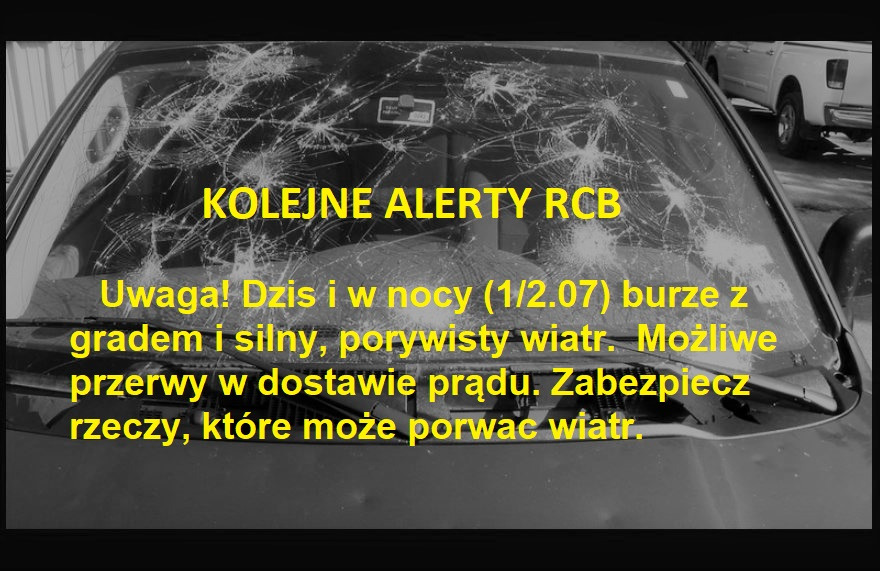 Rozbite przednia szyba samochodu z komunikatem ostrzegawczym o burzach z gradem i silnym wietrze.