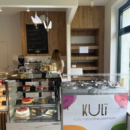 OLIWIA GUMIŃSKA OLIV. DESIGN - Wnętrze kawiarni z ekspozycją ciast i lodów, menu wypisane kredą na tablicy, oświetlenie w kształcie motyli, nowoczesny design.