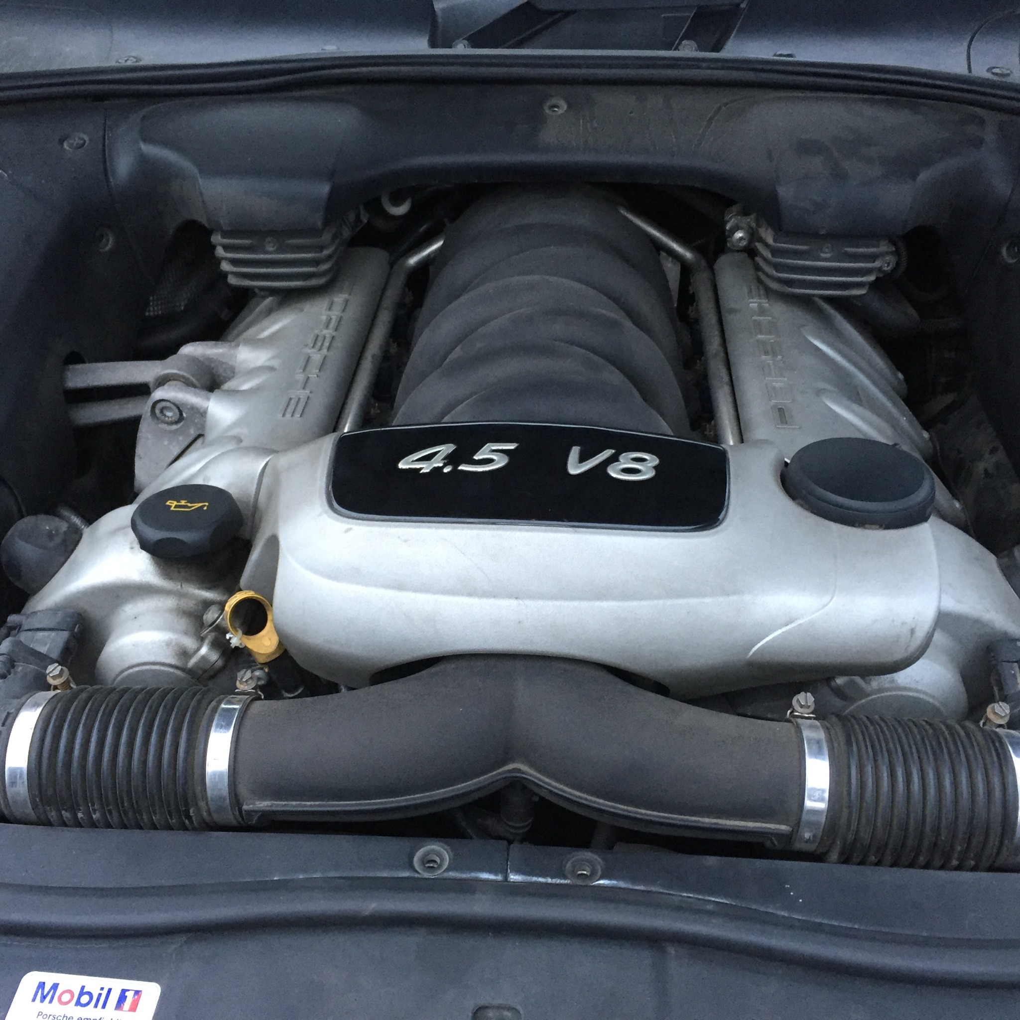 Silnik Porsche 4.5 V8, widoczne elementy układu dolotowego i pokrywa silnika z oznaczeniem pojemności.