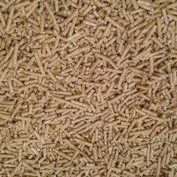 Beżowe granulki biopaliwa z bliska, równomiernie rozłożone i oświetlone z góry.