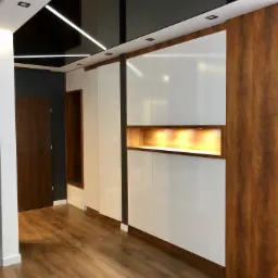 Nowoczesne wnętrze z białą szafą wnękową z drewnianymi akcentami i podświetlaną niszą, odbijające światło w czarnym, błyszczącym suficie z liniowym oświetleniem LED, uzupełnione drewnianą podłogą...